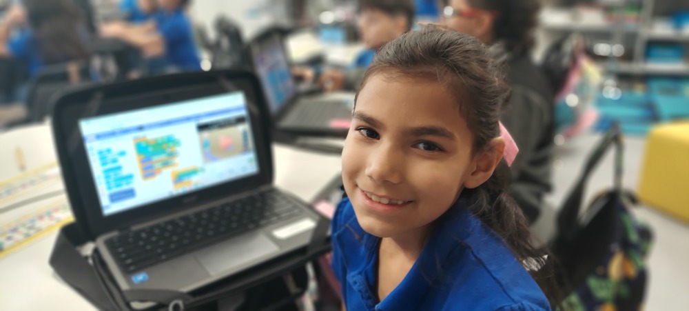 Female student poses for pictures while coding.
