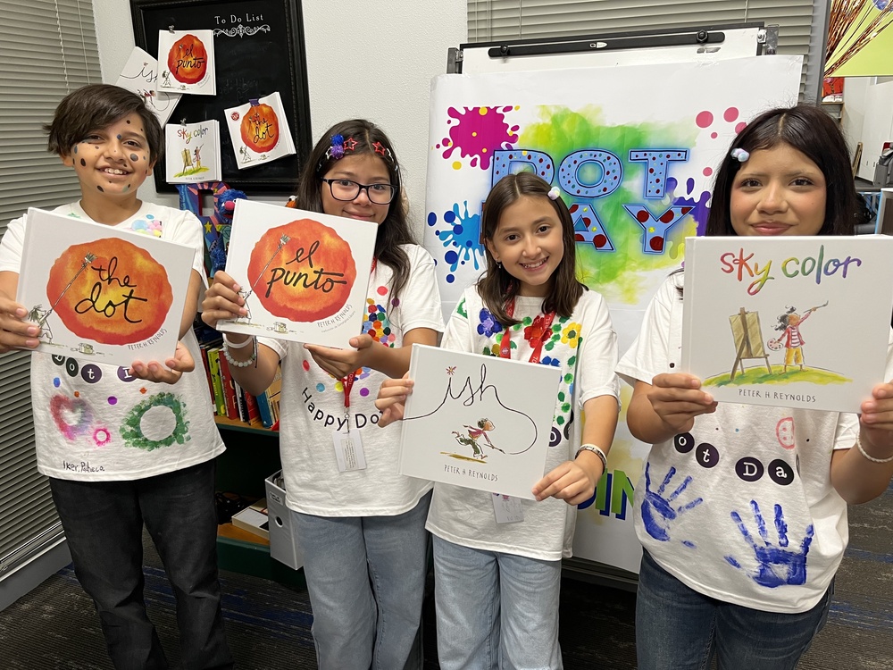 4 students posing with the book "The Dot" by Peter H. Reynolds