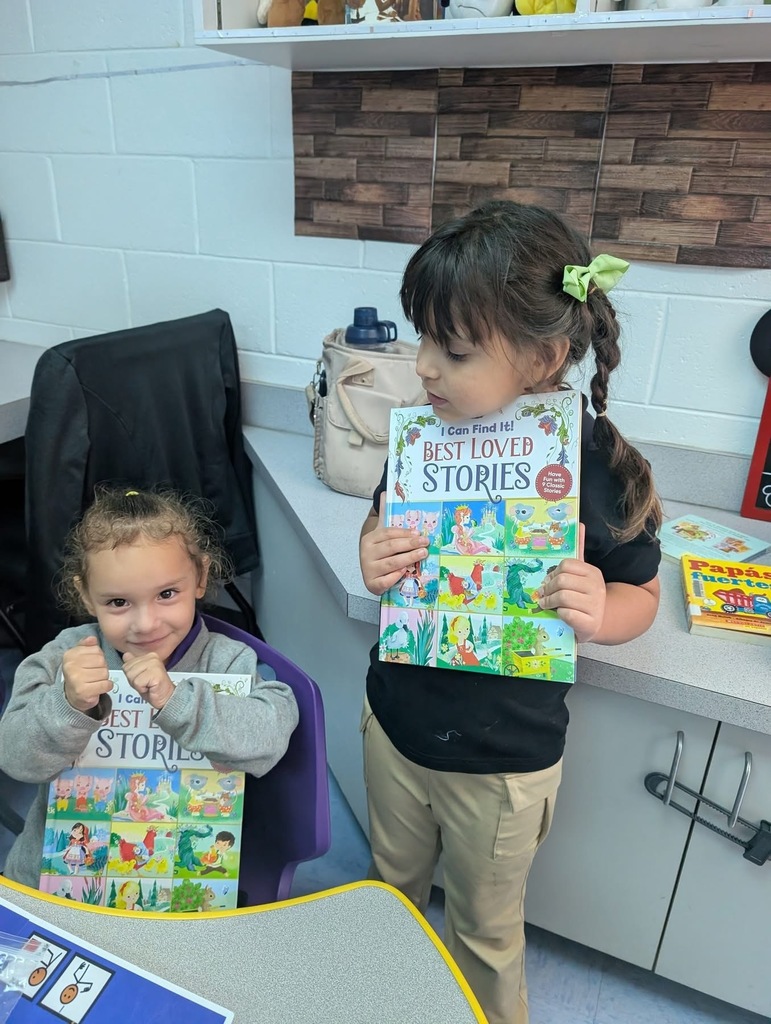 Students sitting down holding up their new books. 