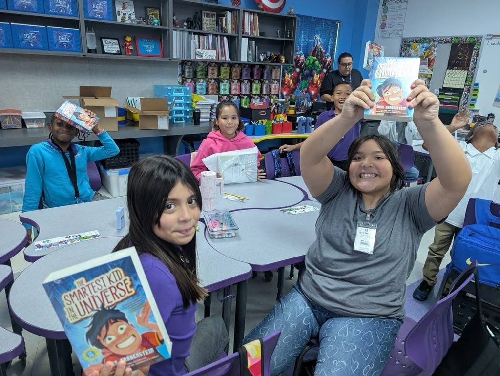 Students sitting down holding up their books. 