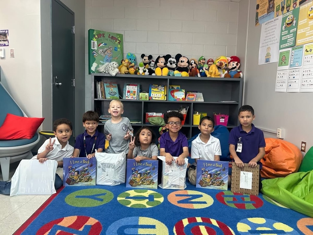Students sitting down holding up their books. 