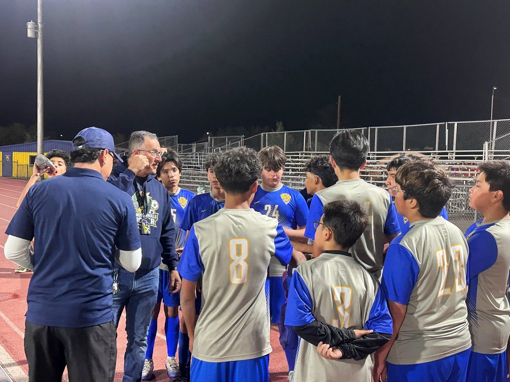 Photo of the 8th-grade soccer team meeting with their coach.