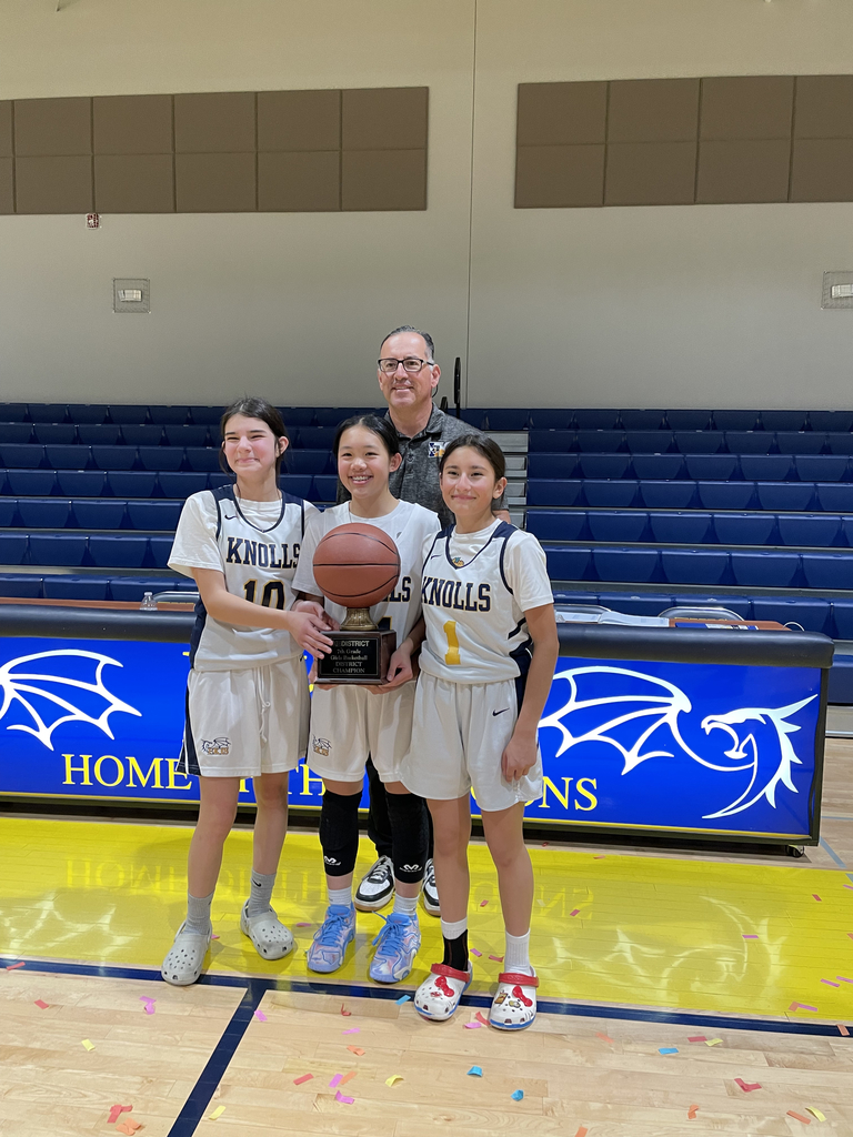 Photo of EKIS 7th grade basketball players with their head coach holding the trophy.