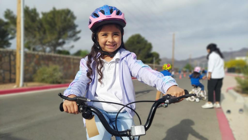 A female student poses for a picture on her bike. She is riding her bike at school for Kinder Bike Day.