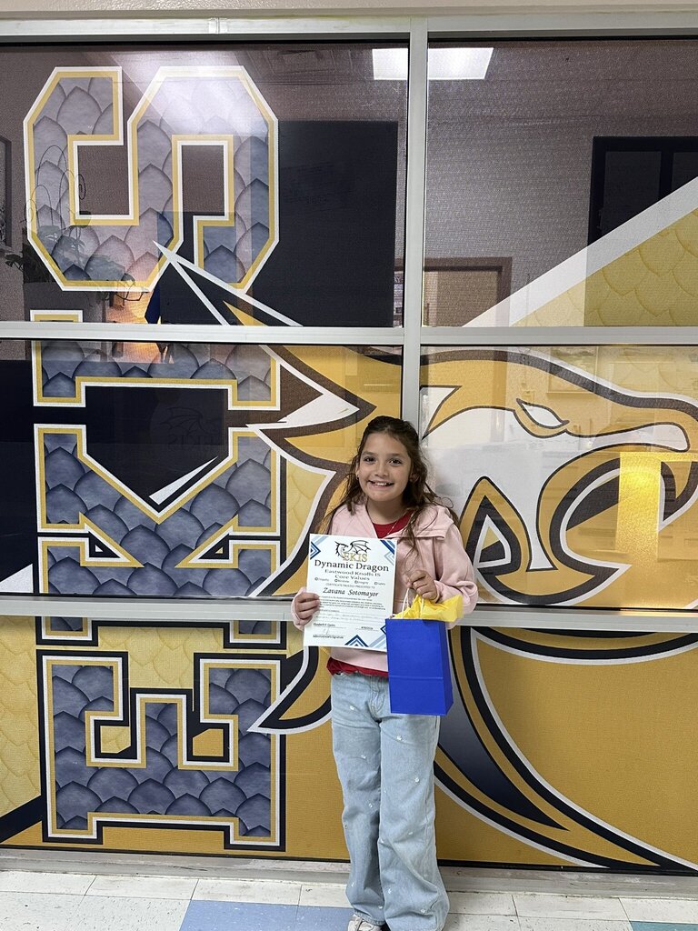 Photo of EKIS student Zavana, receiving a Dynamic Dragon Certificate for demonstrating core school values, Empathy, Kindness, Integrity, and Safety.