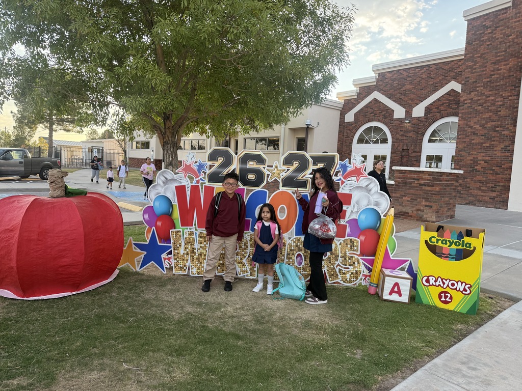Students pose in front of a yard sign welcoming them back to school.