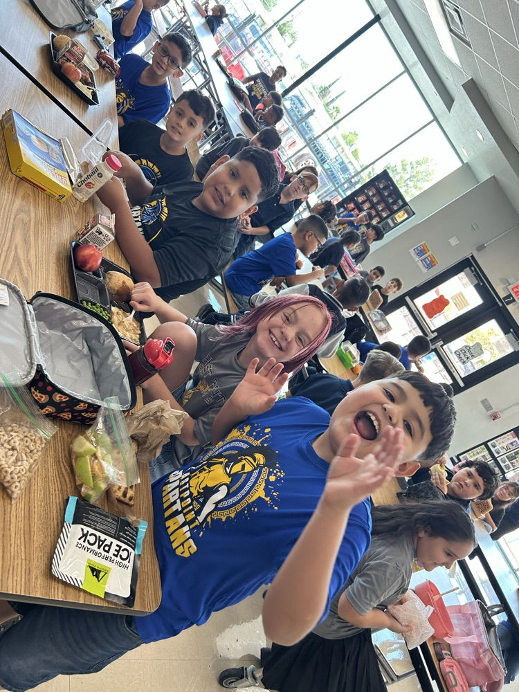 students waving at camera in cafeteria 