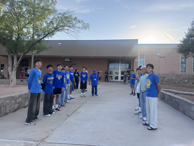 boys from basketball team posing for pictures at entrance to school