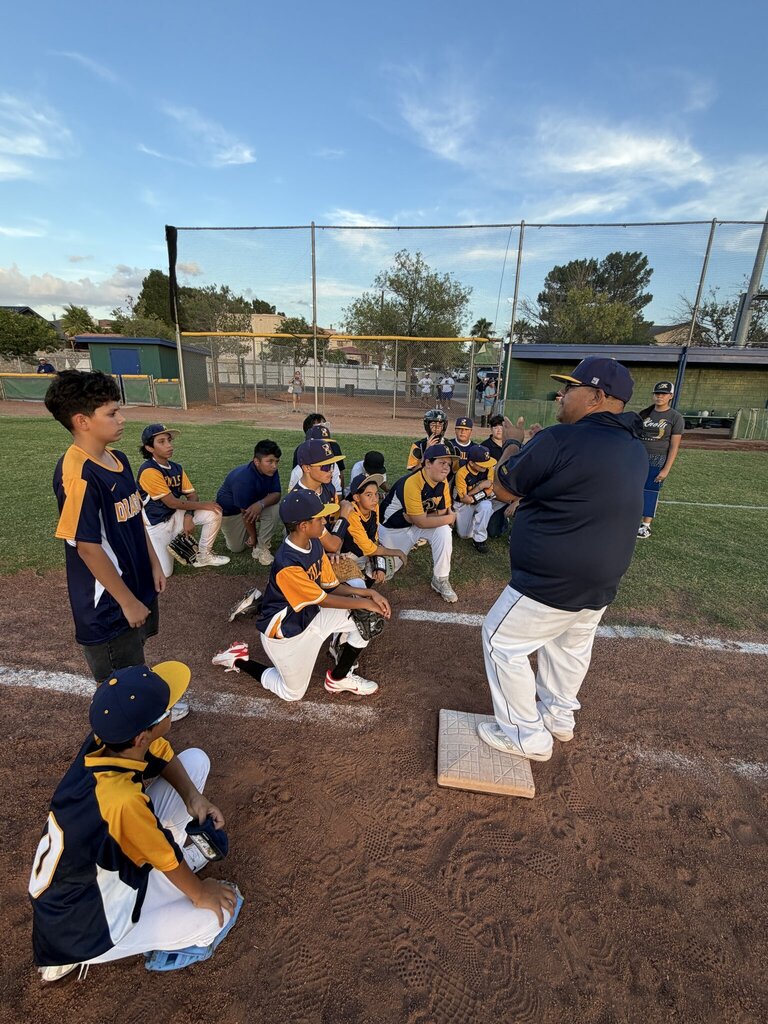 Photo of EKIS baseball team members at a baseball game meeting with Coach Garcia.