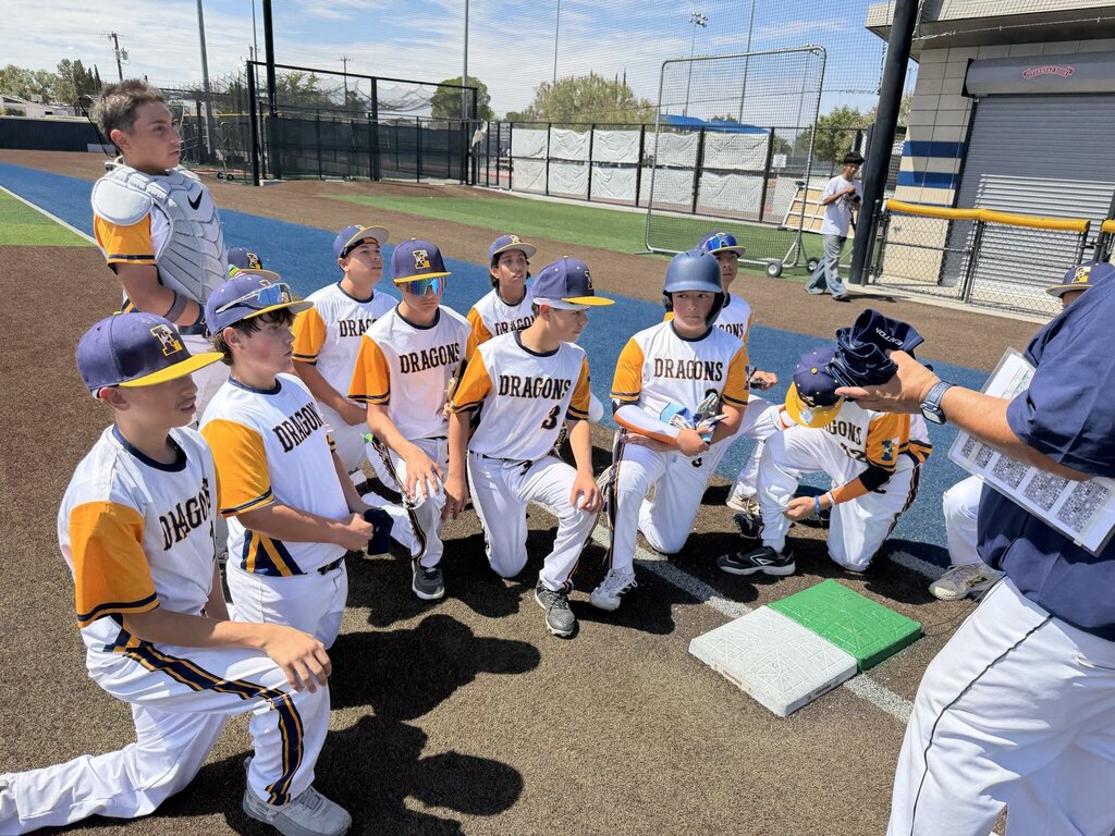 Photo of EKIS baseball team members gathered around Coach Garcia and Coach Medrano.