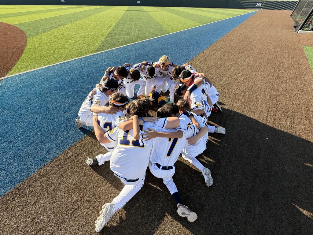 Photo of EKIS baseball team members huddled before a game.