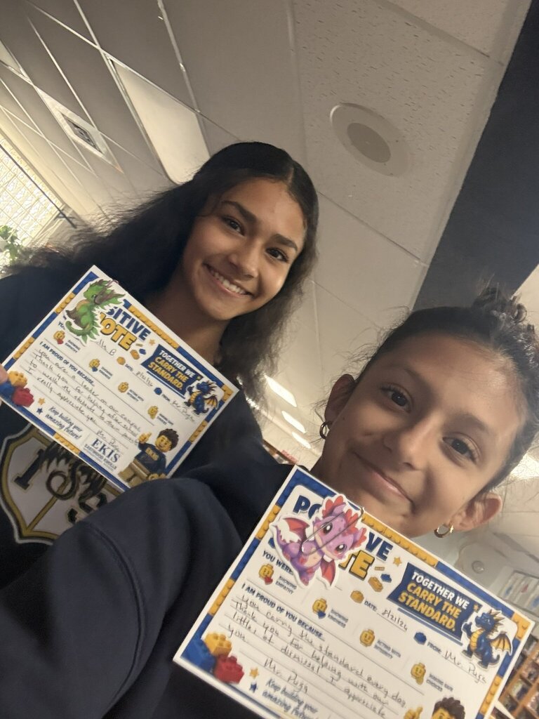 Photo of two EKIS students receiving a positive note for their kindness and empathy.
