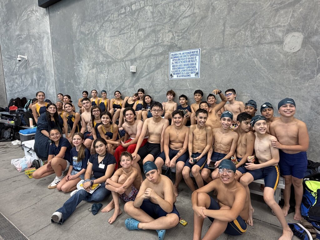 Photo of EKIS Swim team members at the district competition sitting on the bleachers.
