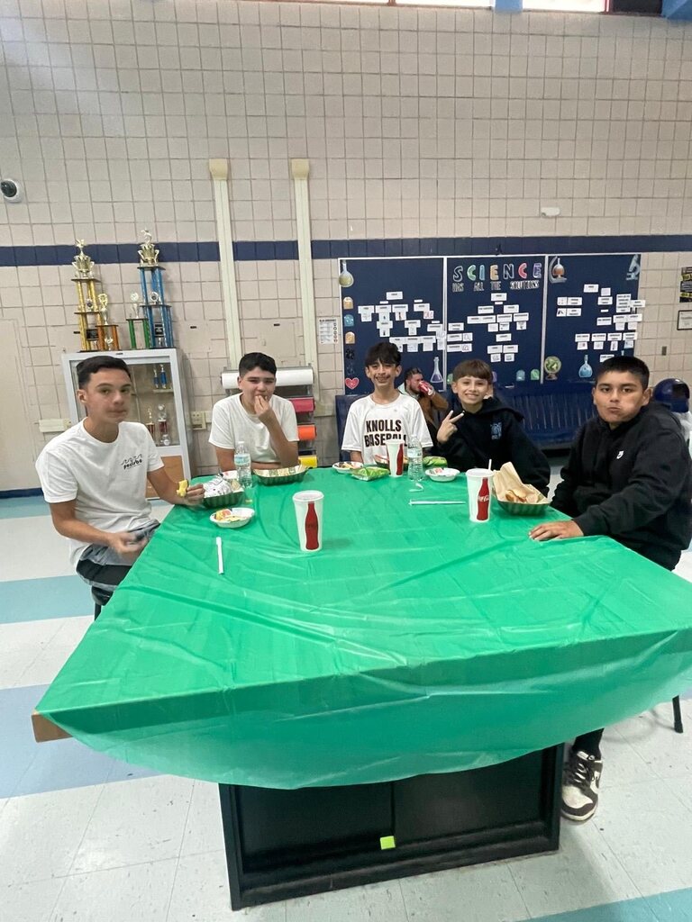 Photo of EKIS football players sitting in groups and eating at a team dinner.