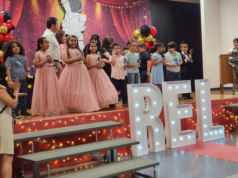 Several of the 2nd graders standing on stage holding their trophies.