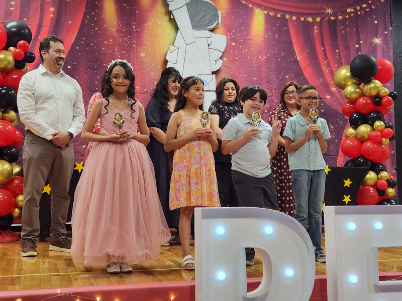 Four second grade students standing in front of their teachers after having received medals for their achievement in Math