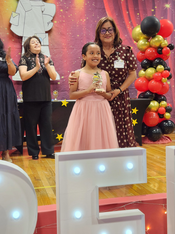 Ms. Muñoz and her student posing for a picture on the stage after receiving an award.