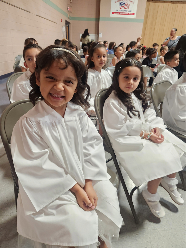 Pre-Kinder students in their graduation robes sitting waiting for the awards ceremony to start