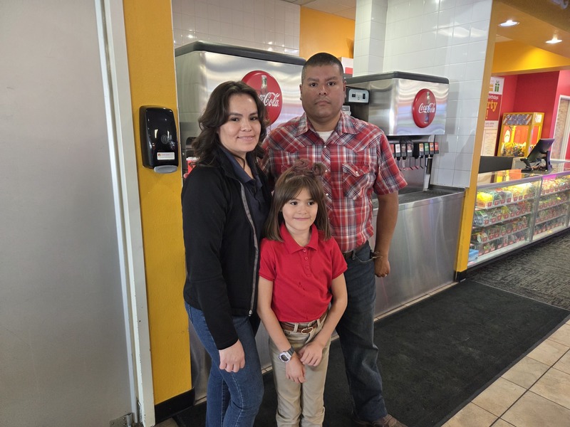 4th grader with her parents stand by the soda dispensers for a photo