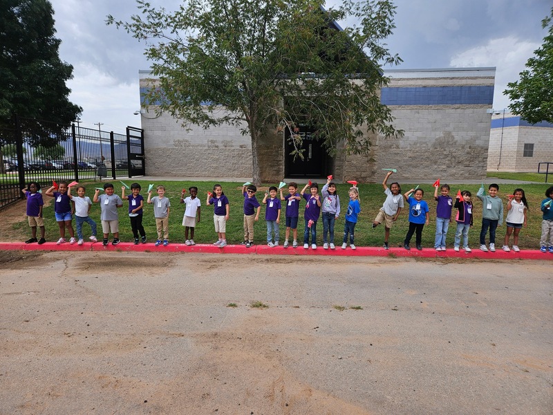 Students holding up paper airplane. 