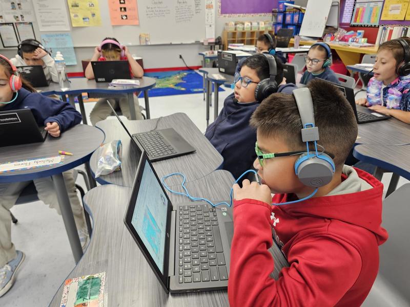 3rd grade boys speaking into their microphones for the Amira app to practice reading