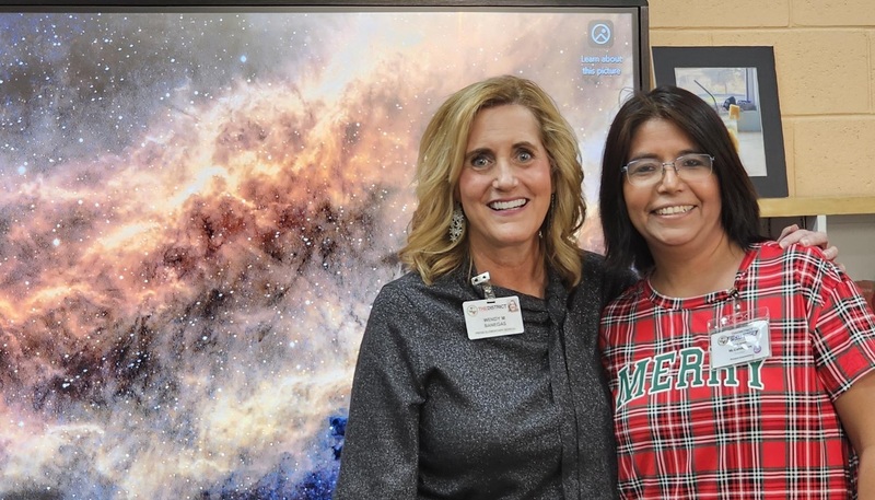 Ms. Banegas and Ms. Calderon pose in the library