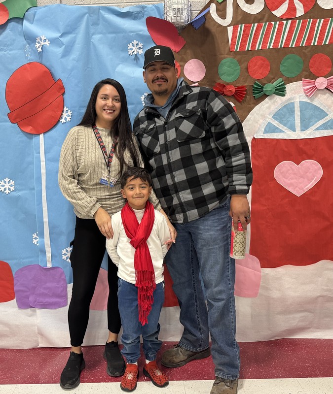 Mom and Dad with son and his red scarf pose in front of the candy store