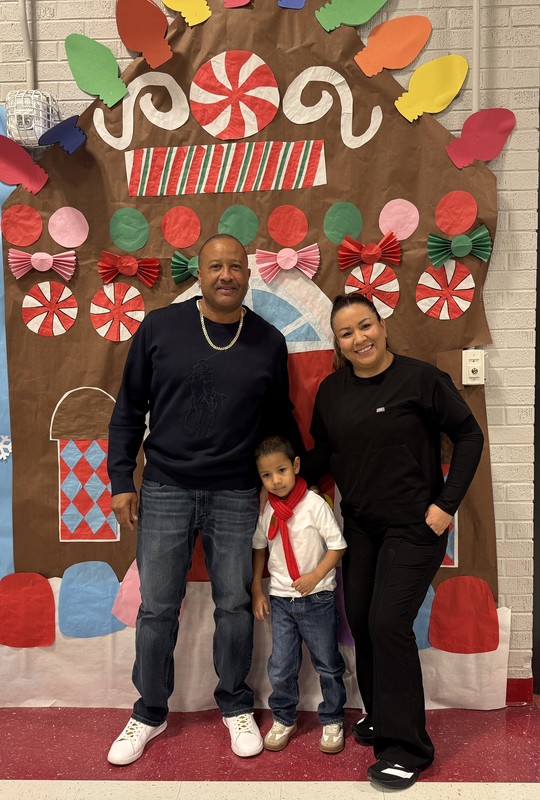 Mom and Dad pose with their child in front of the candy store decoration