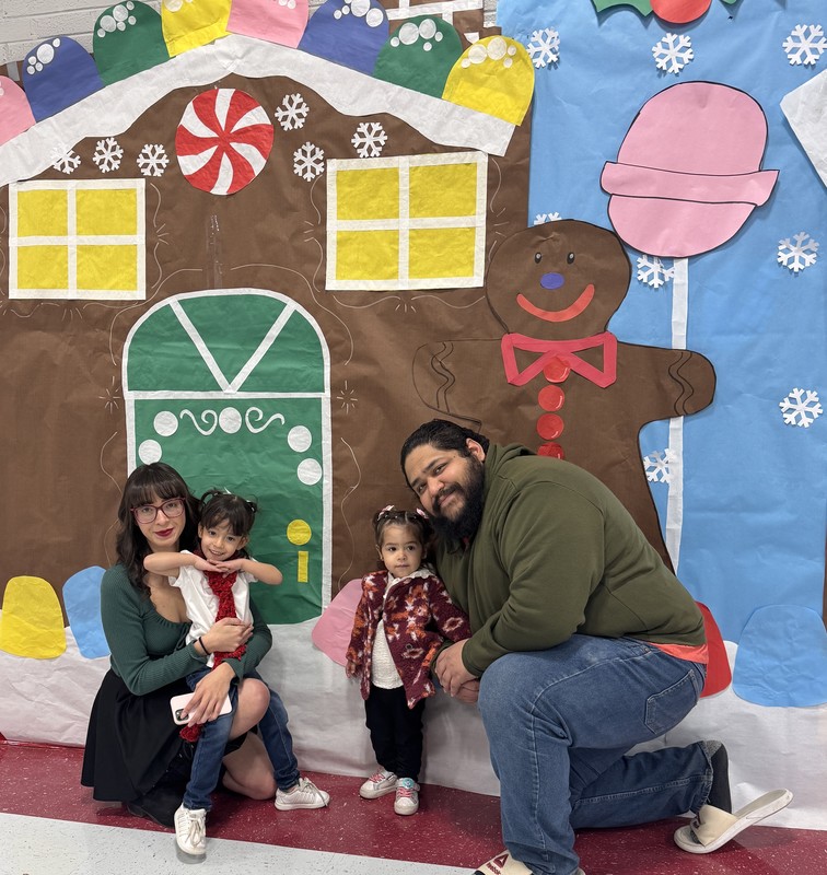 PK student's family pose in front of the Gingerbread house decoration