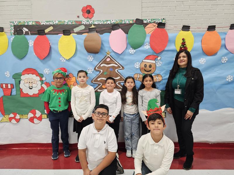 Mrs. Murillo and her class takes a quick picture in front of the Santa Train decoration.