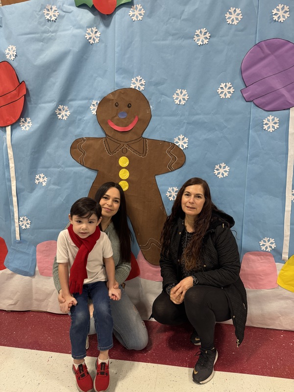 Mom and Grandma pose with PK child in front of Gingerbread backdrop