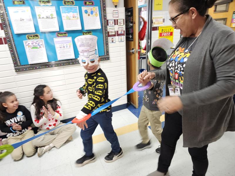 Mrs. Martinez walks with her students that are wearing a 100 day parade hat and sunglasses