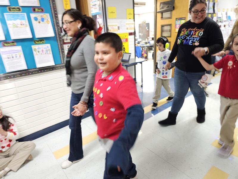 Student walks with Teacher Assistant in the 100 day parade