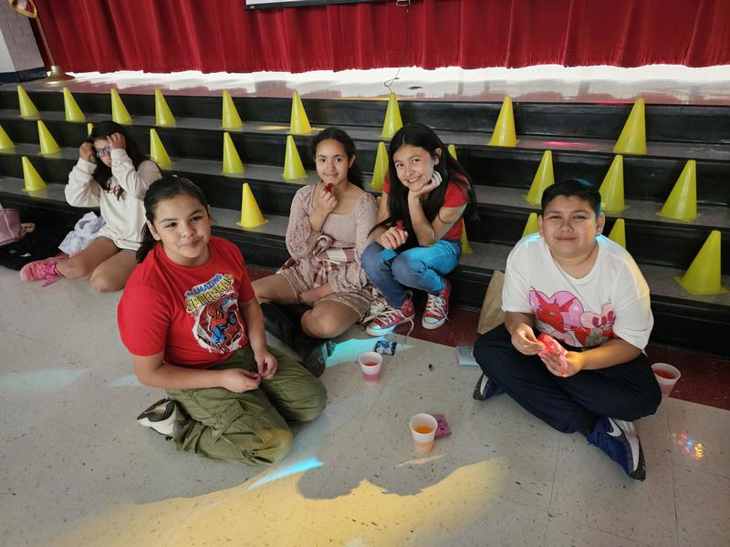 5th graders take a break and eat snacks sitting at the steps of the stage