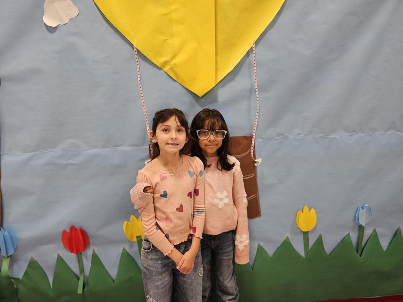 2nd grader girl besties pose under the hot air balloon backdrop