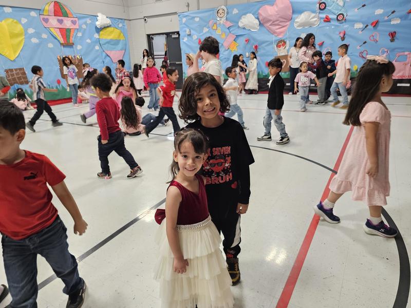 PreK girl in a dress and Kindergarden boy in a black shirt smile for the camera