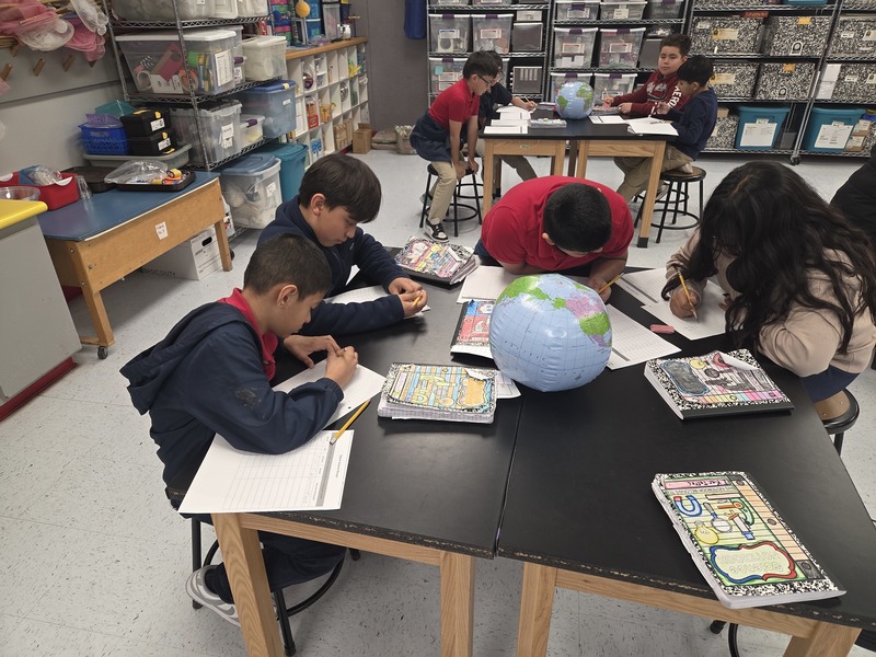4th graders collaborate around a science table and record their finding