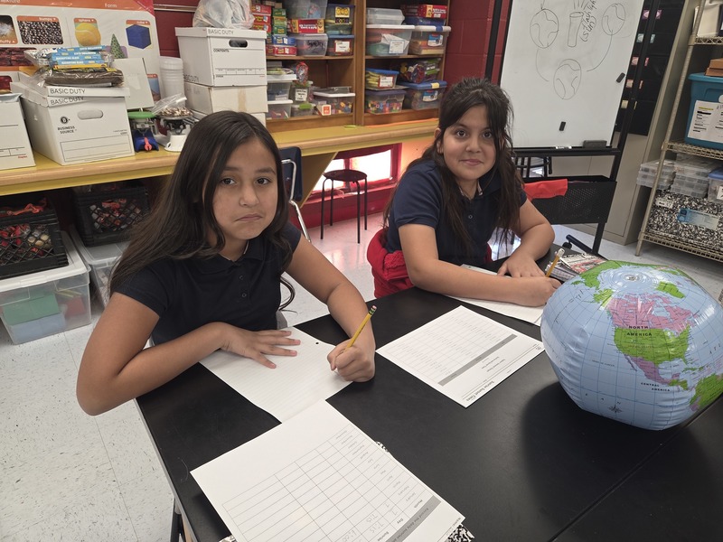 4th grade girls smile as they work on their data collection