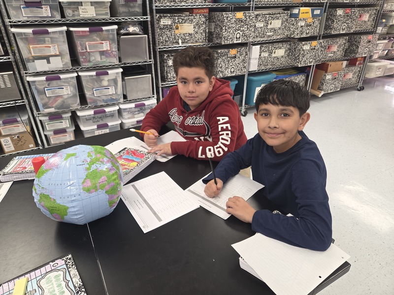 4th grade boys smile while recording their data in Science