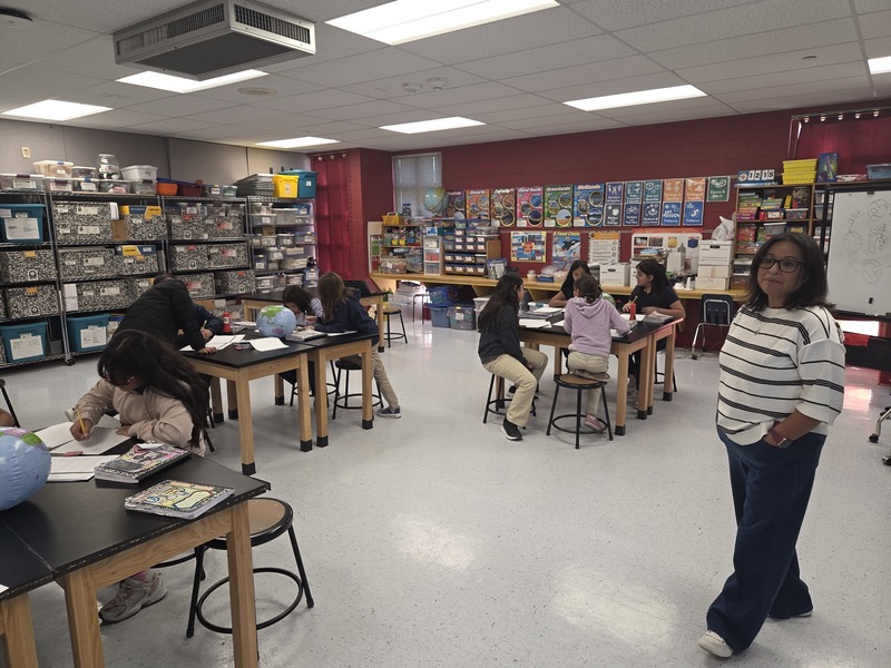 Mrs. Vela poses for a pic while her students work at their Science tables recording information