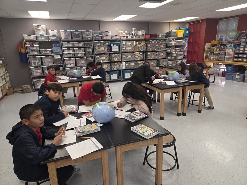 4th graders work around science lab tables gathering and recording information