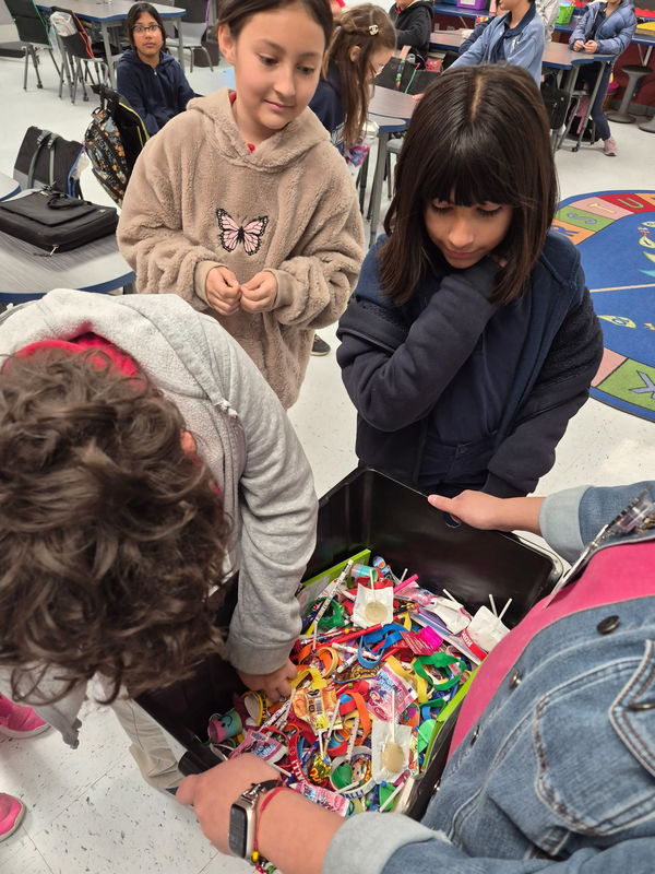 4th grader digs into the treasure chest for a prize with 2 onlookers