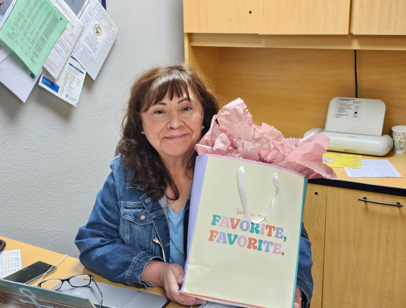 Ms. Jacquez in her office with a gift bag showing the words favorite, favorite 