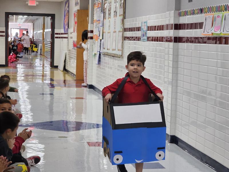 The 1st PK student walks down the hallway with his blue car model