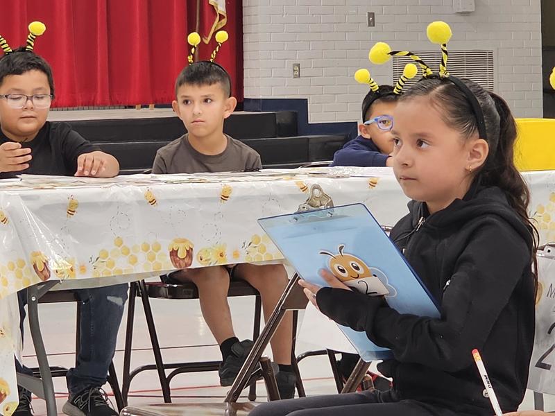 Final Contestant thinking about a problem on paper while her classmates look on
