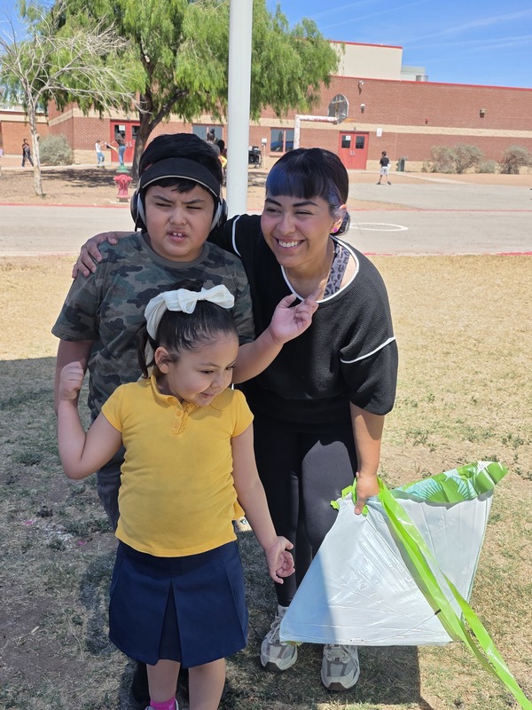 Mother and her son and daughter with a green kite pose for a photo
