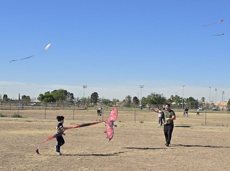 young boy and parent trying to catch wind for their red dragon kite