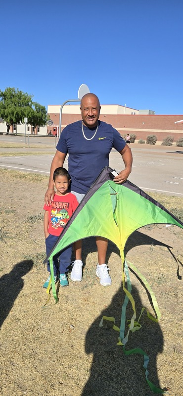 Father and son pose with their green florescent kite
