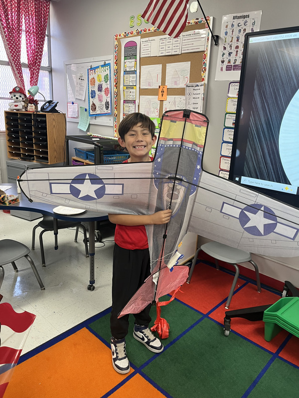 Student proudly stands showing off his bomber plane kite