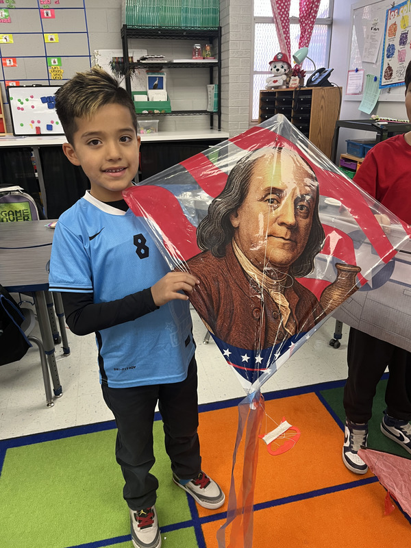 Student proudly stands with his Ben Franklin kite